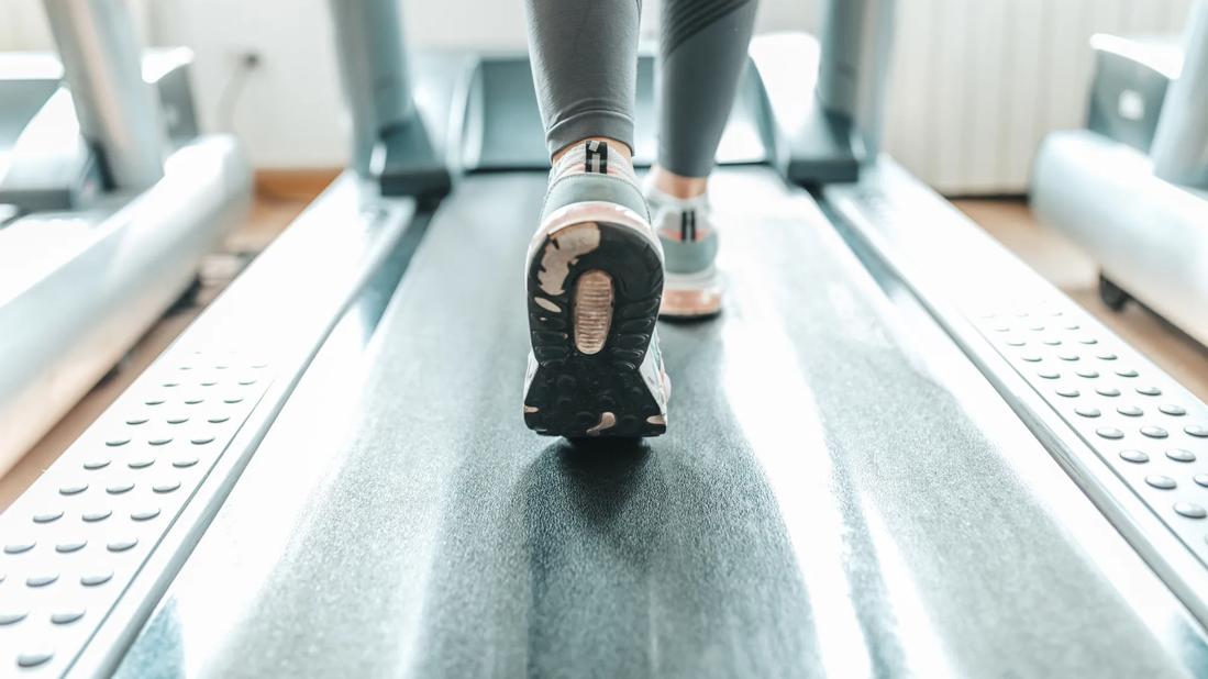 Legs and feet of person on a treadmill at the gym