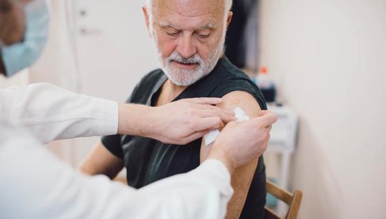 Healthcare provider applying a bandage on arm of person after injecting a shot