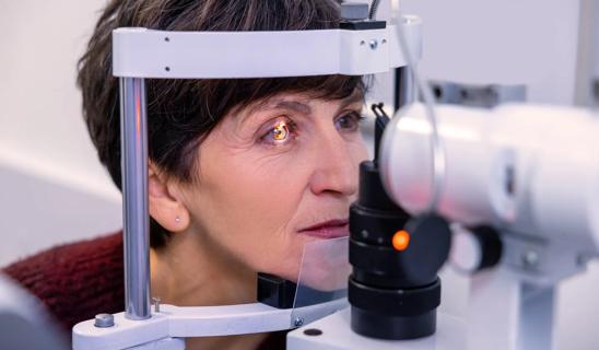 Person positioned in a slit lamp machine, receiving an eye exam