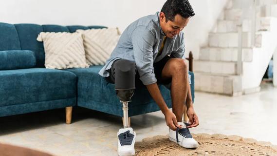 Man with leg prosthetic tying shoe