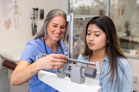 Healthcare provider taking patient's weight and height measurements