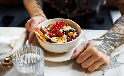 Person at table with a bowl filled with fruits and grains