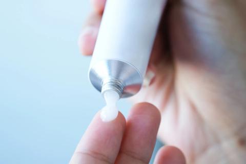 Hand squeezing cream from a tube onto a finger