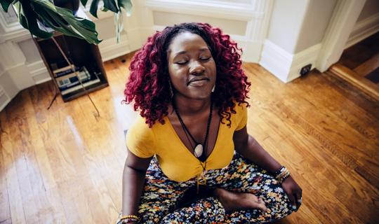Person relaxing in seated yoga pose at home