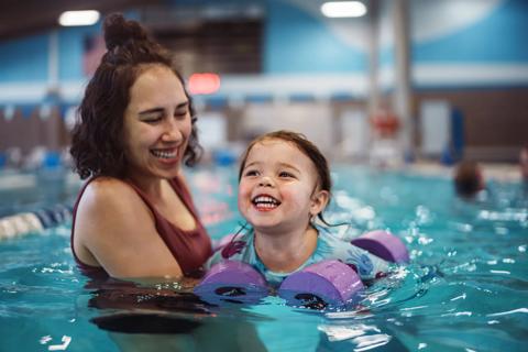 Child in pool receiving a swimming lesson